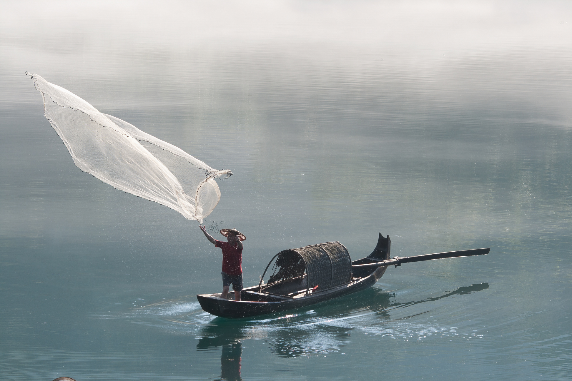 Fisherman casting net on river